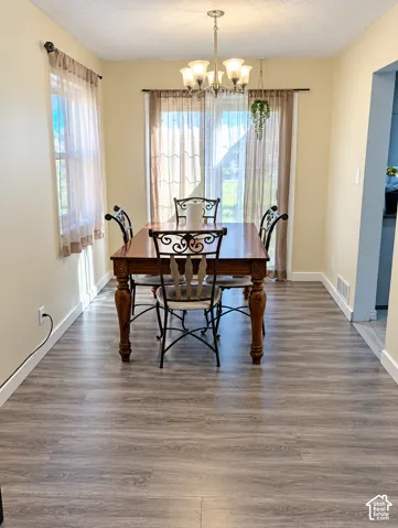 Dining space featuring wood-finish flooring, a five-arm multi-light chandelier, and glass sliding doors