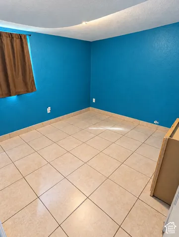 Interior room featuring neutral-toned tile flooring, textured blue walls, and a curved ceiling design