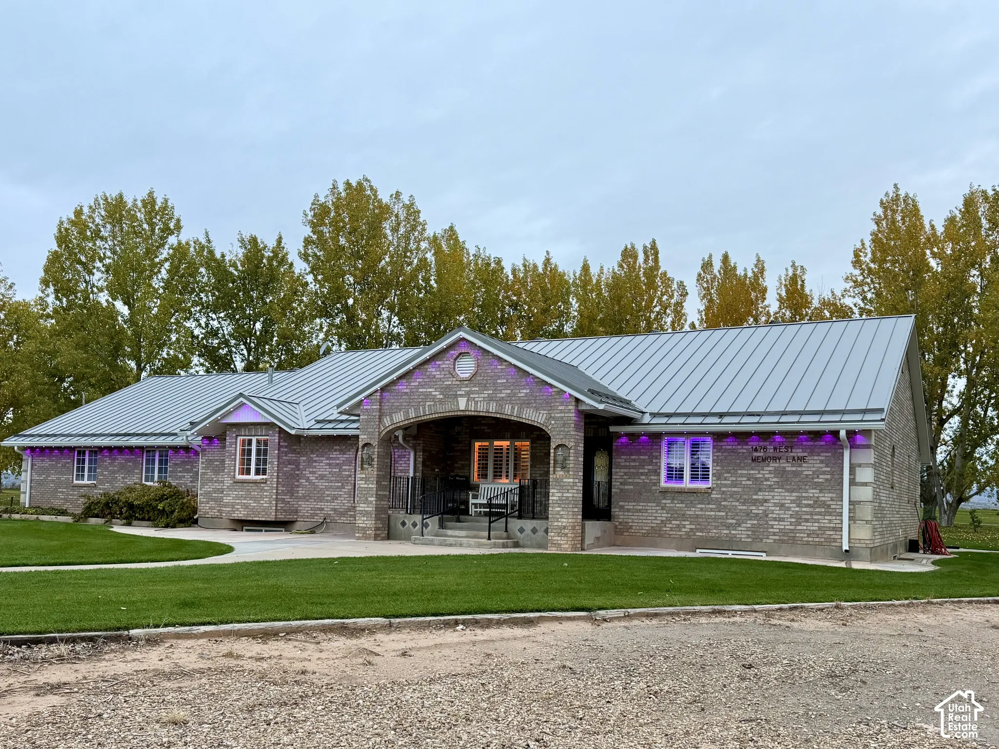 Brick exterior featuring a metal roof, arched covered entryway, and a concrete walkway