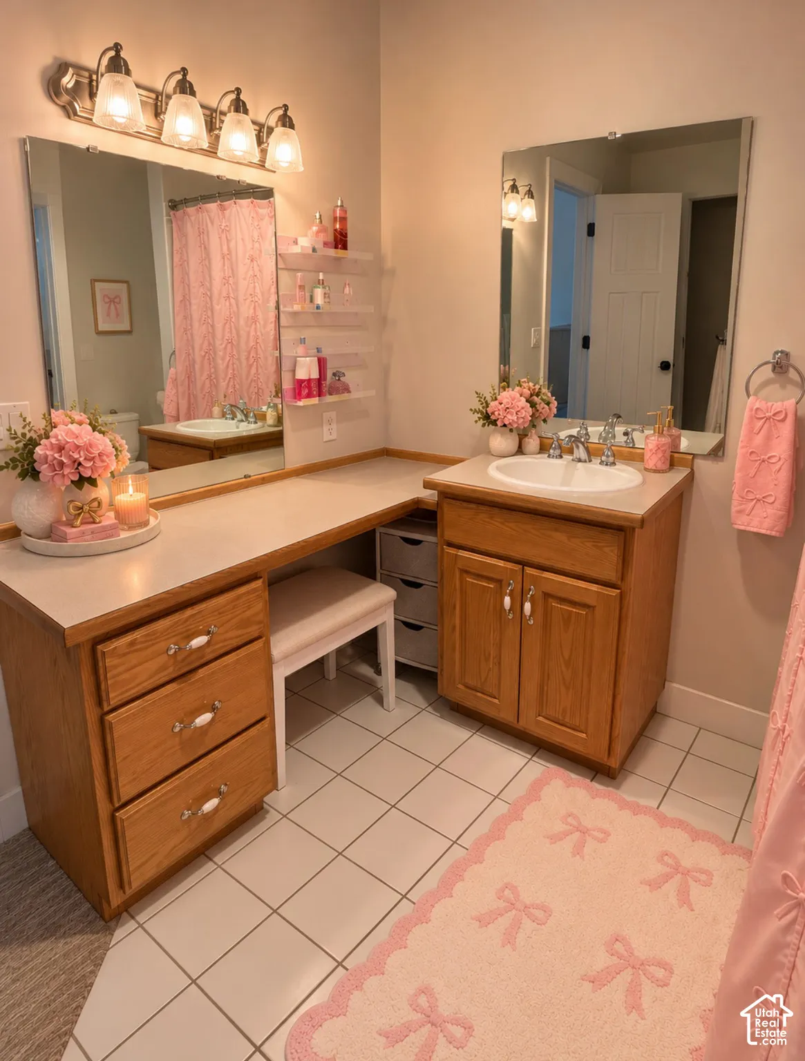 L-shaped wood cabinetry featuring a built-in vanity, white tile flooring, dual wall-mounted vanity mirrors, and a four-light fixture
