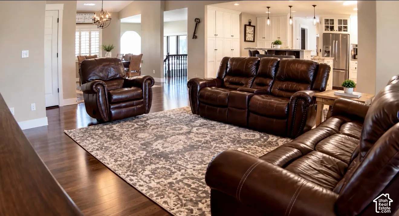 Open-concept living space featuring wood-finish flooring, white floor-to-ceiling cabinetry, recessed lighting, and a kitchen island with pendant lighting
