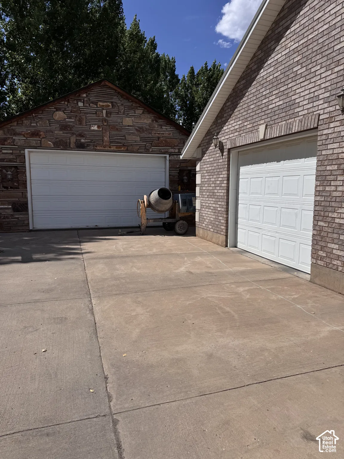 Exterior featuring multi-car garage space, stone masonry detailing, brick facade, and concrete driveway