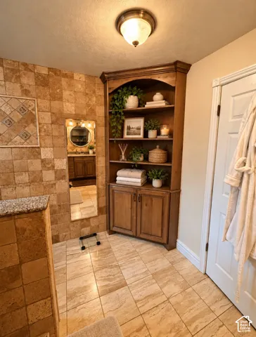 Custom built-in corner cabinetry, natural stone wall tile, stone floor tile, and flush-mount lighting fixture