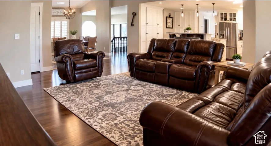 Open-concept living space featuring wood-finish flooring, white floor-to-ceiling cabinetry, recessed lighting, and a kitchen island with pendant lighting