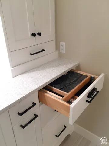 Built-in white cabinetry featuring matte black hardware, speckled composite countertop, and a drawer equipped with an integrated electronic keypad lock