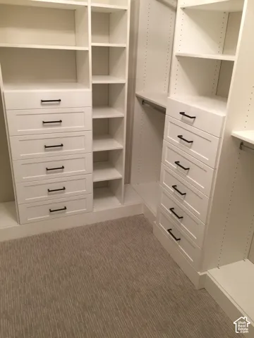 Custom walk-in closet featuring white built-in cabinetry, multiple drawers with matte black hardware, integrated shelving, and hanging rods