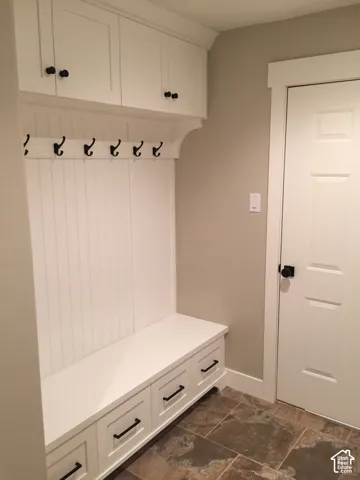 Built-in cabinetry with beadboard detailing, upper storage lockers, lower drawers, matte black hardware, and slate-finish tile flooring