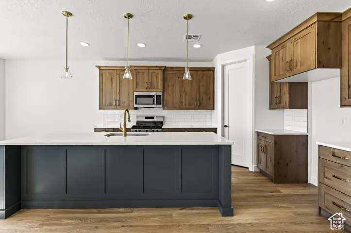 Kitchen featuring a center island with quartz countertops, wood-finish cabinetry, subway tile backsplash, and brass-tone pendant lighting