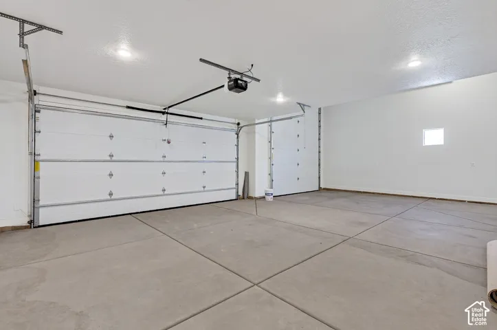 Attached multi-car garage featuring finished walls, concrete flooring, recessed lighting, and automated garage door openers