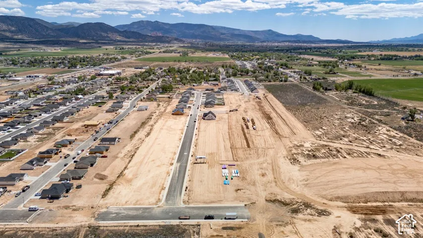 Aerial perspective of a development parcel featuring paved streets, utility infrastructure, and mountain topography