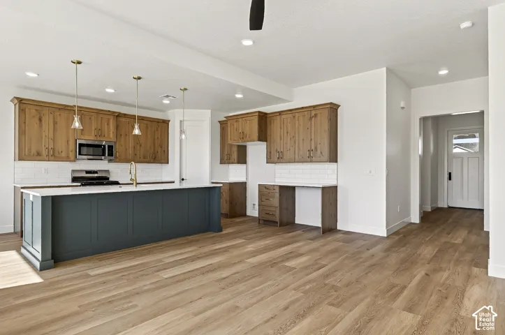 Kitchen featuring wood-finish cabinetry, a large central island with a contrasting finish, white subway tile backsplash, recessed lighting, and wood-finish flooring