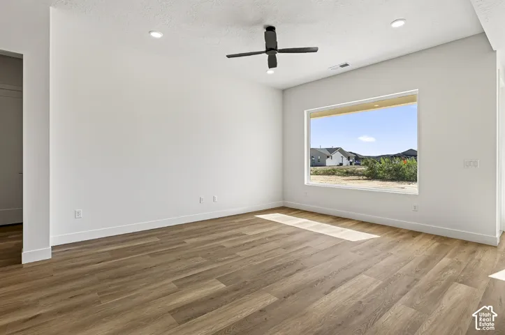 Interior space featuring wood-finish flooring, a large picture window, recessed ceiling lighting, and a matte black ceiling fan