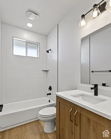 Bathroom featuring a vanity with a white solid-surface countertop, wood-finish cabinetry, matte black fixtures, and a tub-shower combination with white subway-style tile surround
