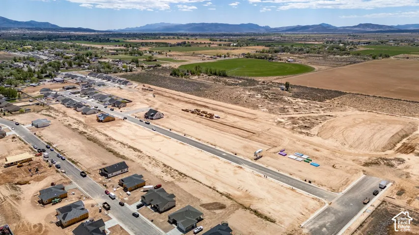 Aerial perspective of a developing residential community featuring paved roadways, graded land parcels, and mountain horizons