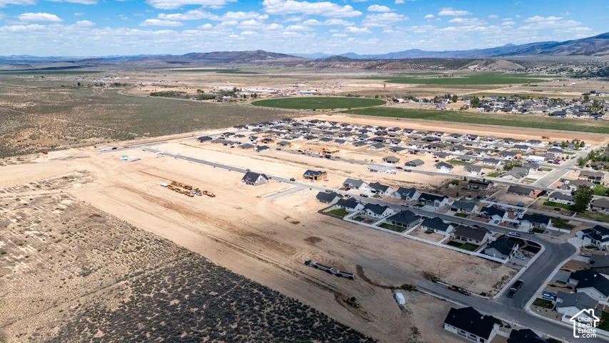 Aerial perspective of expansive residential development featuring paved streets, multi-lot infrastructure, and surrounding mountain terrain
