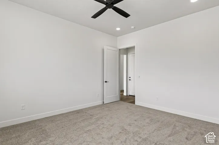 Neutral interior featuring wall-to-wall carpeting, vaulted ceiling, matte black ceiling fan, and shaker-style interior doors with matte black hardware