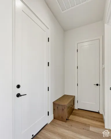 Interior hall featuring white shaker-style doors with matte black hardware and wood-finish flooring