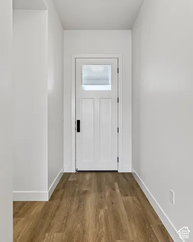 Entryway featuring wood-finish flooring, white walls, and a single-panel door with an upper glass insert and matte black hardware