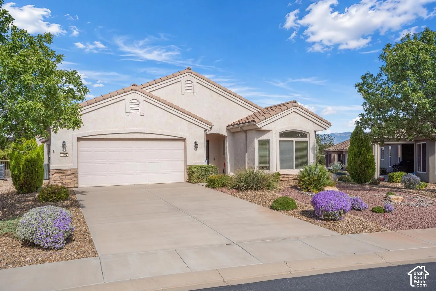 Single-story stucco exterior with stone accents, tile roof, and two-car garage