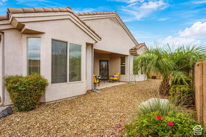Exterior stucco finish with tile roofing, bay window configuration, covered patio, and desert-inspired rock landscaping