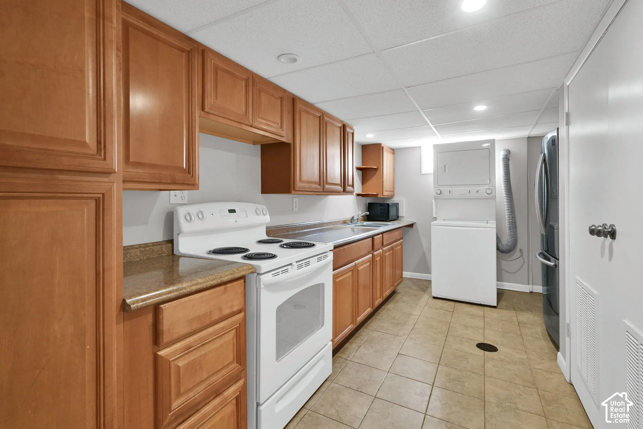 Kitchenette featuring wood-finish cabinetry, solid surface countertops, a white electric range, and ceramic tile flooring