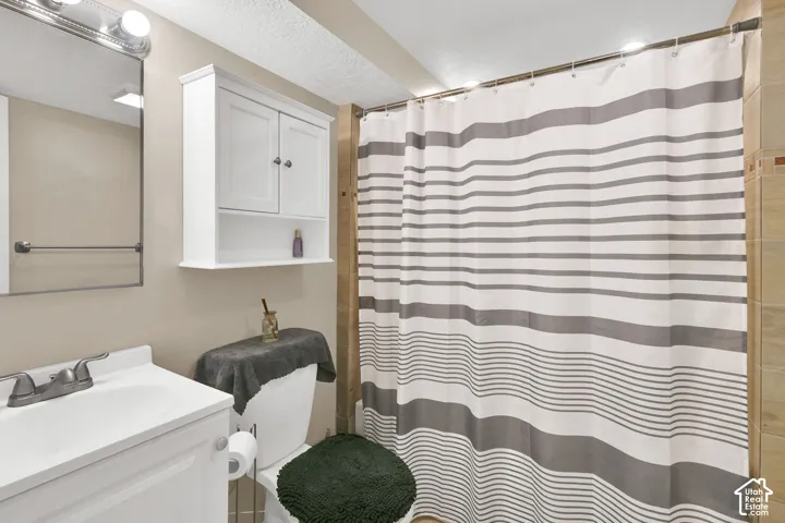 Bathroom featuring a white vanity cabinet, wall-mounted storage cabinet, framed mirror, and tile shower surround