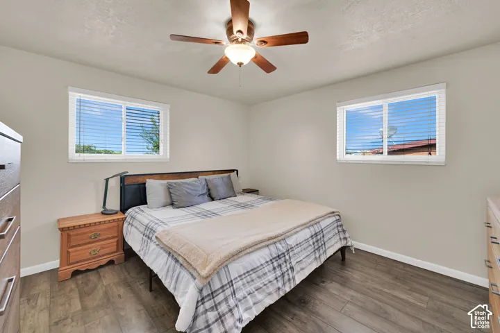 Neutral-toned walls paired with wood-finish flooring, dual windows, and a ceiling fan with integrated lighting