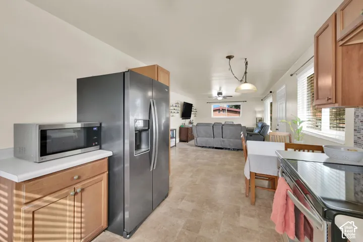 Kitchen featuring wood cabinetry, solid-surface countertops, tile flooring, and pendant lighting