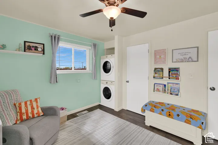 Utility space featuring stacked laundry appliances, horizontal sliding window, and ceiling-mounted light fixture with fan