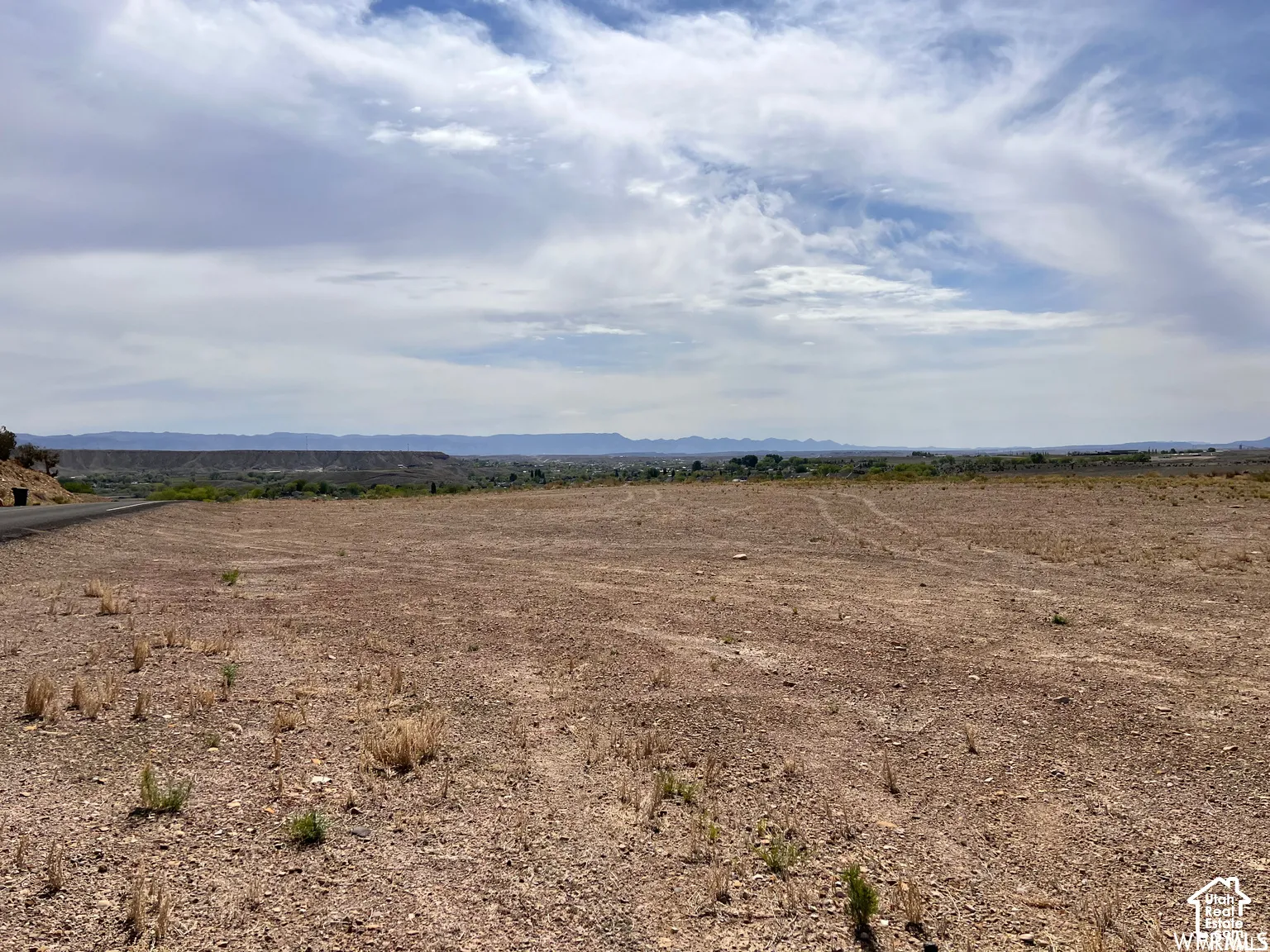 Expansive vacant parcel featuring native desert landscape, paved road access, and distant mountain topography