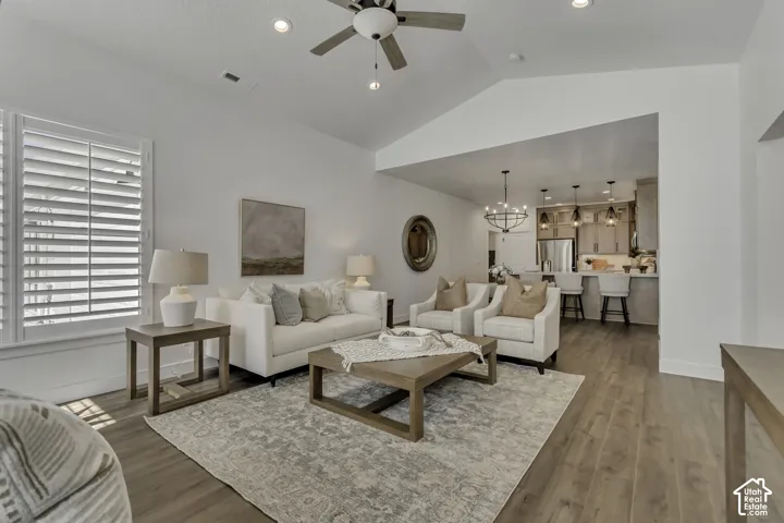 Vaulted ceilings, wood-finish flooring, plantation shutters, recessed lighting, and a kitchen island with pendant lighting