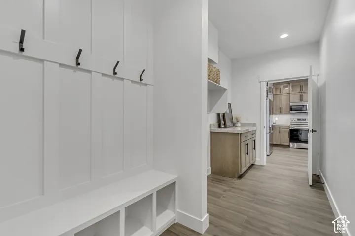 Mudroom featuring built-in white bench seating with storage cubbies, vertical board-and-batten wall detailing, and matte black hardware