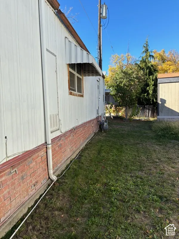 Exterior wall featuring vertical metal siding, lower brick masonry, and a metal window awning