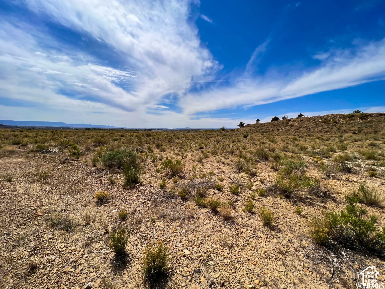 Expansive desert acreage featuring native shrubs, rocky terrain, and distant mountain backdrops