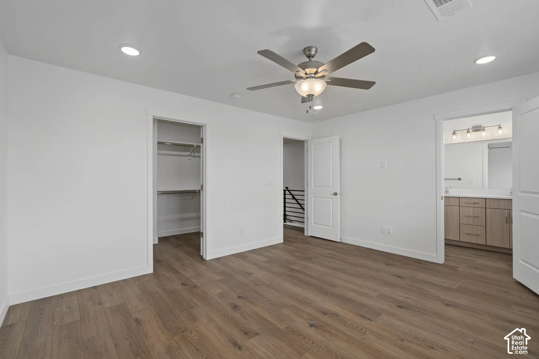 Room featuring LVP wood-finish flooring, recessed lighting, a multi-blade ceiling fan with an integrated light fixture, a walk-in closet, and a bathroom with a melamine wood-finish vanity