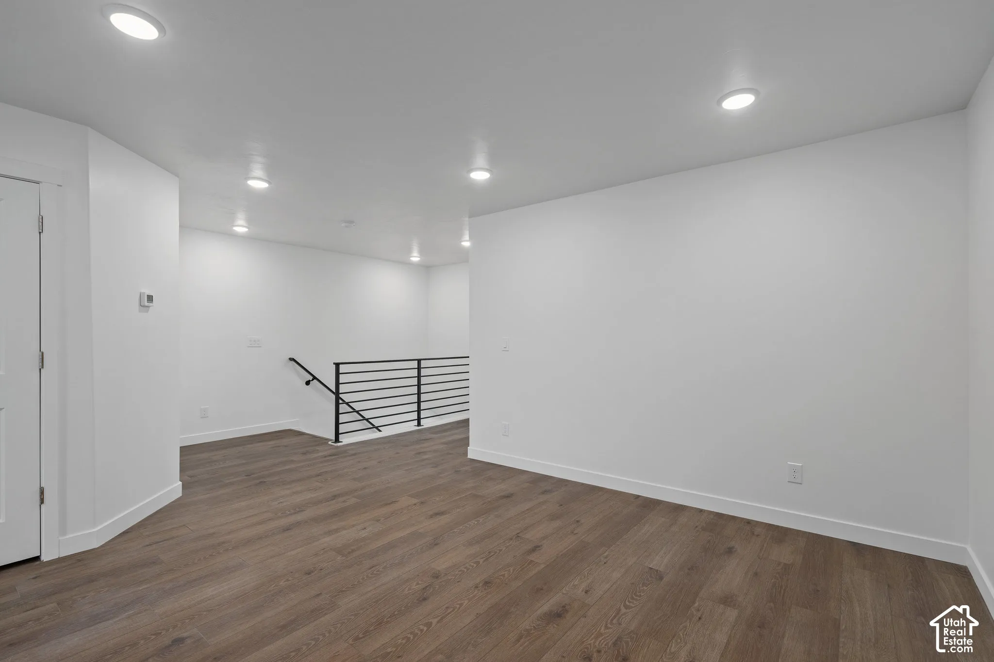 Loft space featuring LVP wood-finish flooring, recessed lighting, and a metal horizontal-bar railing