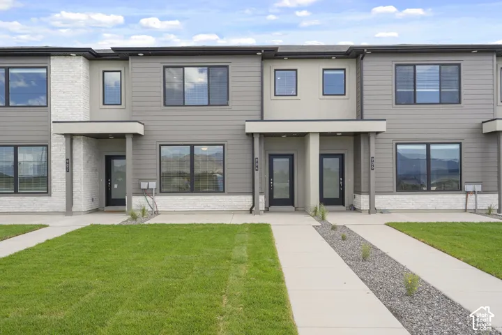 Modern multi-story exterior featuring horizontal siding, light-toned stone masonry veneer, covered entryways, and concrete walkways
