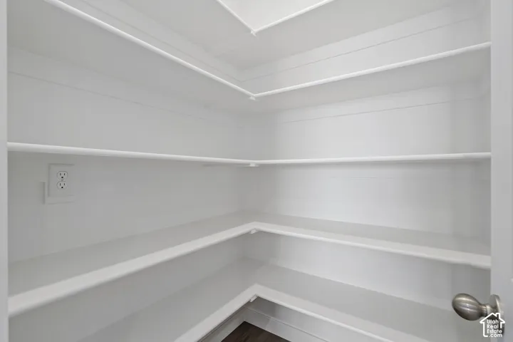 Storage area featuring wrap-around tiered shelving, bright white painted interior, and a built-in electrical outlet