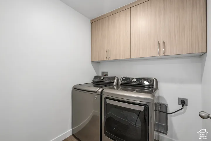 Laundry area featuring wood-finish wall-mounted melamine cabinetry with metallic hardware