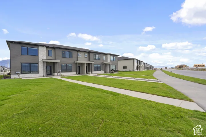 Two-story multi-unit exterior featuring dark horizontal siding, light stone veneer accents, multi-pane windows, and concrete walkways
