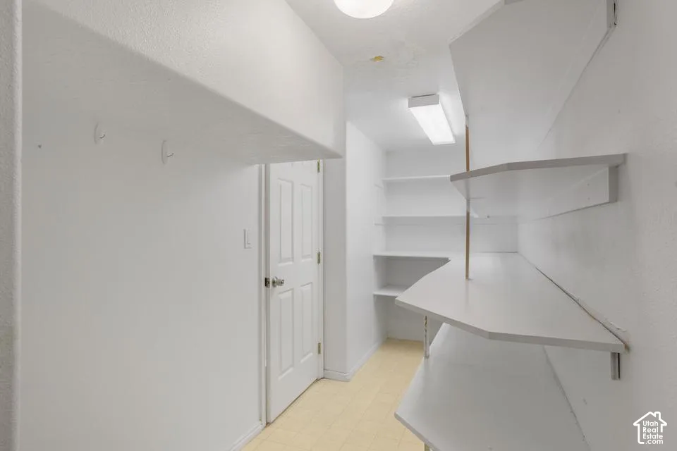 Built-in shelving, white wall-mounted utility hooks, solid-core panel door with metal hardware, and tiled flooring