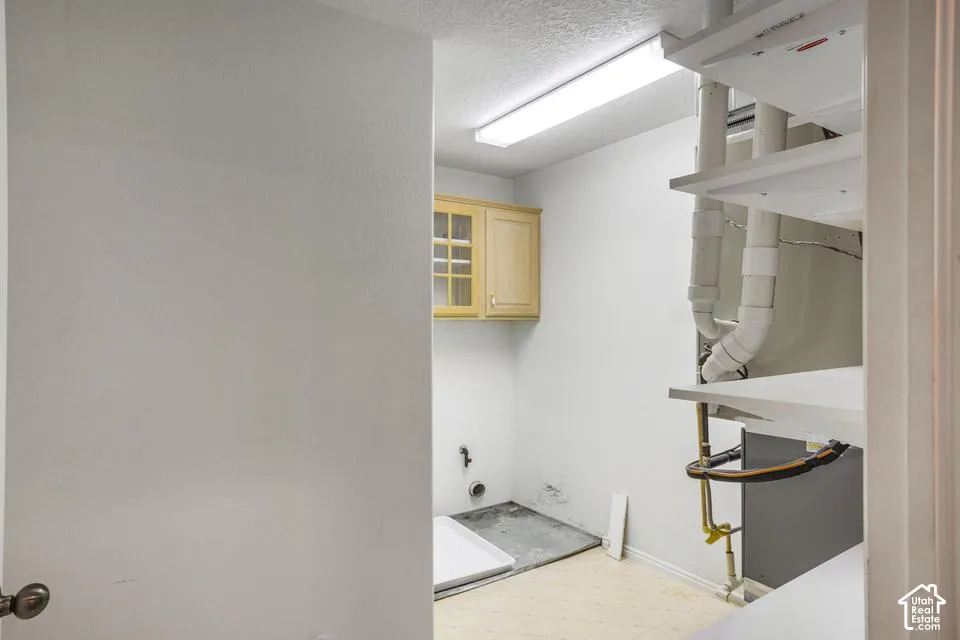 Utility area featuring built-in wood cabinetry with glass-paneled doors, integrated storage shelving, and overhead linear lighting