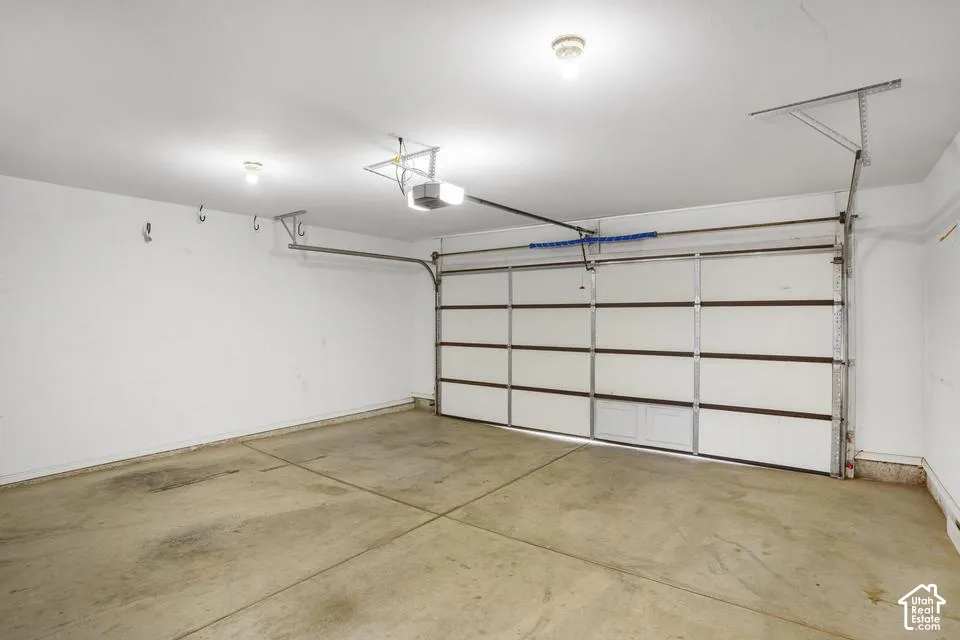 Multi-car garage featuring a sectional overhead door, concrete flooring, ceiling-mounted light fixtures, and an automatic door opener