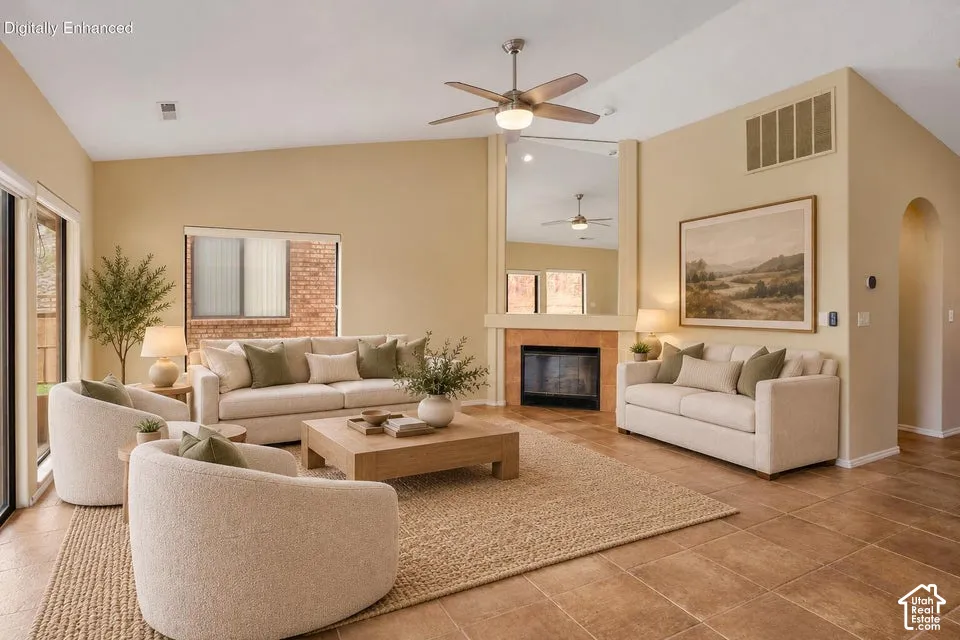 Vaulted ceiling with a central brushed metal ceiling fan, fireplace with a tiled hearth and a floor-to-ceiling mirror, and ceramic tile flooring
