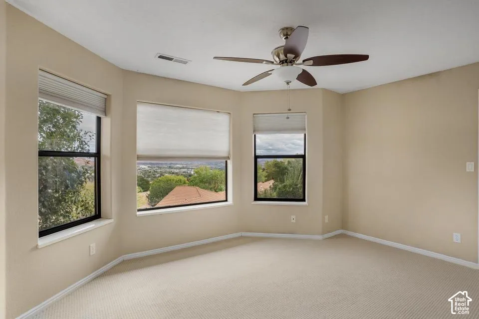 Bay window featuring expansive glazing, neutral carpeting, and a ceiling fan with integrated lighting