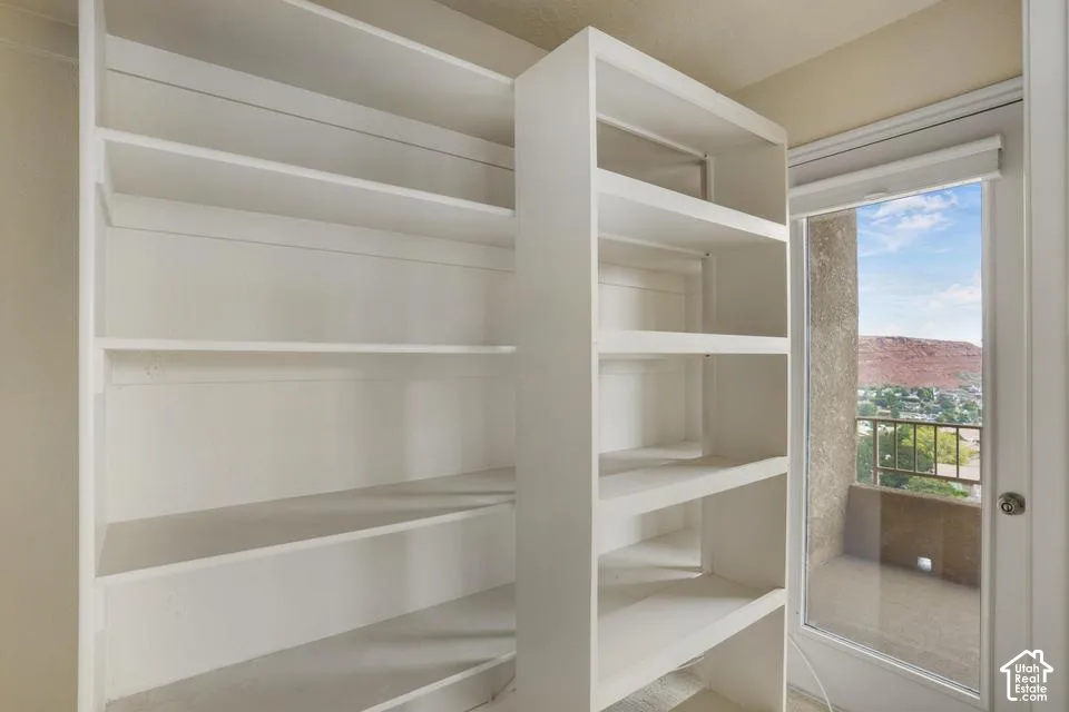 White built-in shelving featuring fixed storage tiers and a glass-paneled door leading to an exterior balcony with mesa landscape surroundings