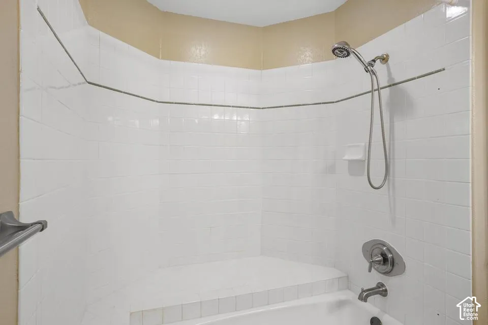 Tiled shower surround featuring a built-in corner bench, brushed nickel handheld shower fixture, integrated soap dish, and wall-mounted towel bar