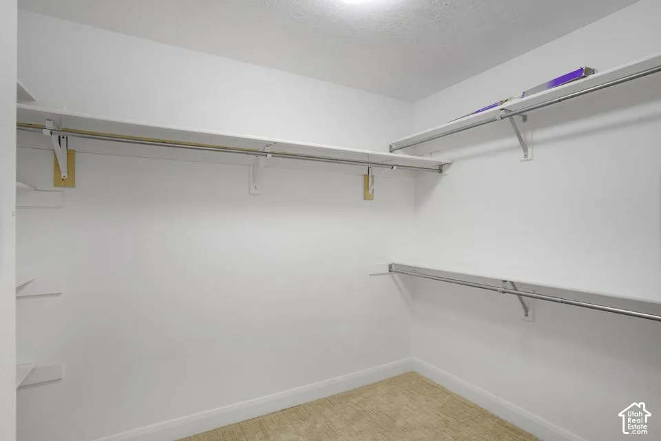 Walk-in closet featuring multi-level built-in shelving, metal garment rods, and carpeted flooring