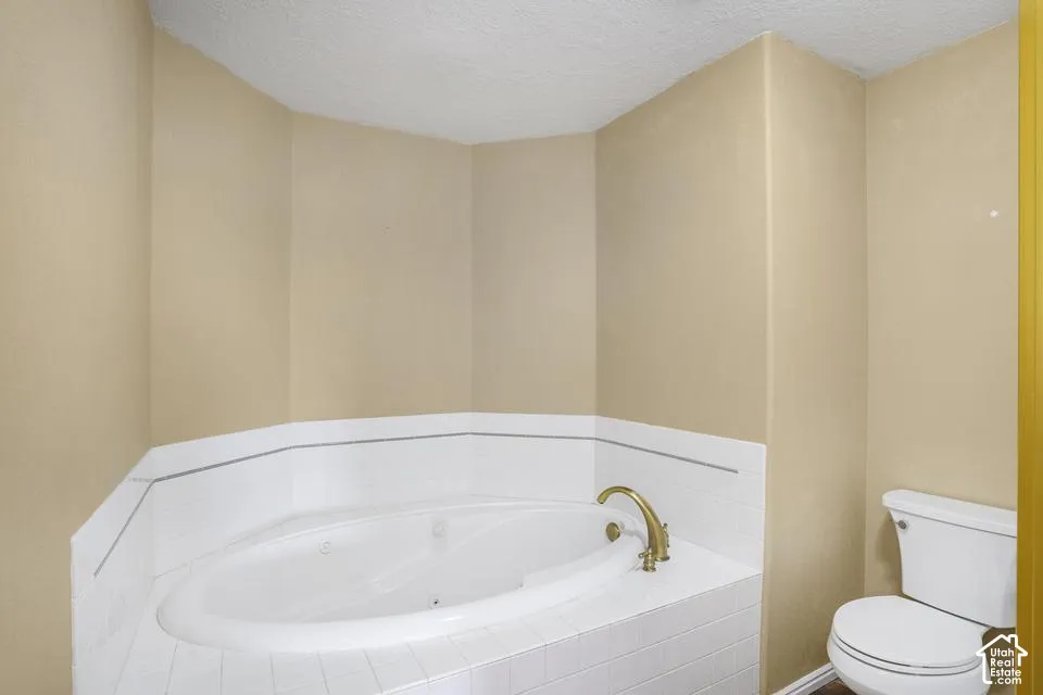 Built-in corner jetted soaking tub featuring a white tile surround and brass-finish faucet