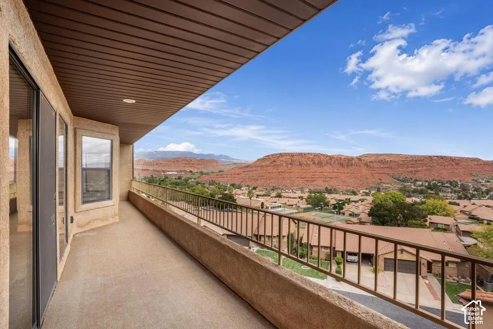Covered balcony featuring concrete flooring, a metal railing, and prominent red rock mountain scenery